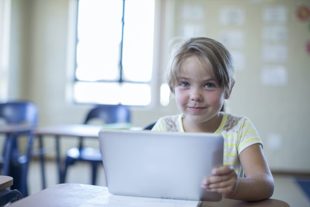 Portrait of smiling primary schoolgirl with digital tablet